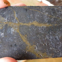Massive magnetic skarn mineralization cut by chalcopyrite (yellow) veinlets